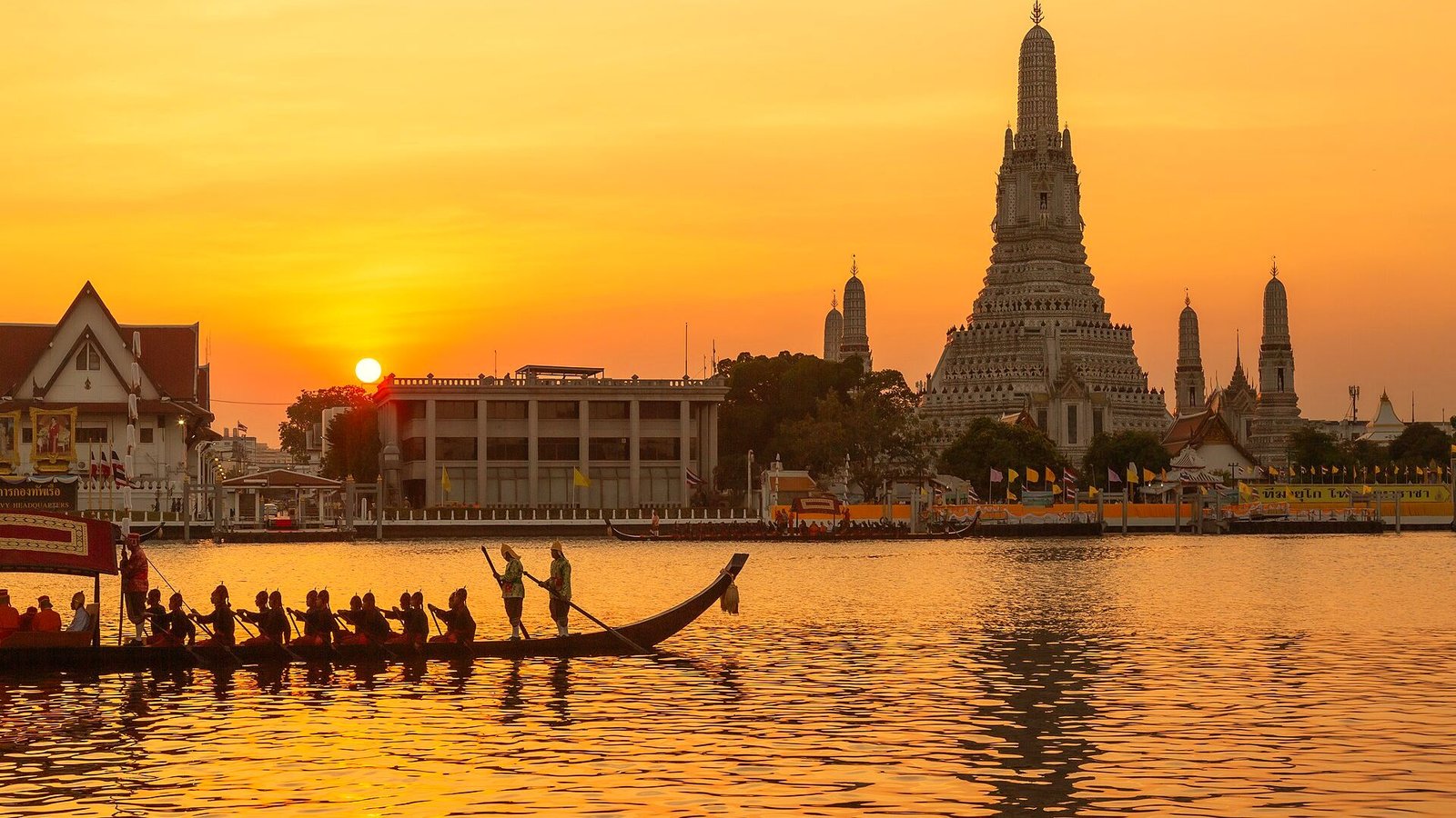 Golden Thai temple glowing at sunset beside the Chao Phraya river in Bangkok